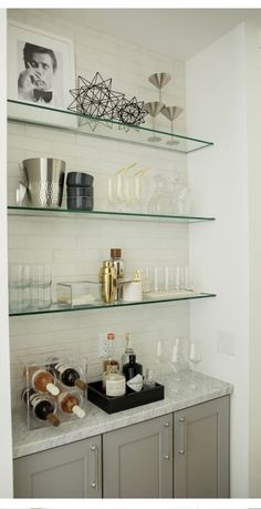 the shelves in this kitchen are filled with bottles and glasses