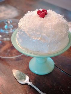 a cake with white frosting and raspberries sitting on top of a table