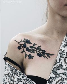 a woman's chest with black flowers and leaves on her left shoulder, in front of a white background