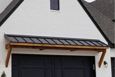 a white brick house with black garage doors