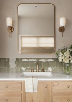 a bathroom with a sink, mirror and flowers in vases on the counter top