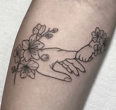 two hands holding each other with flowers on their arm