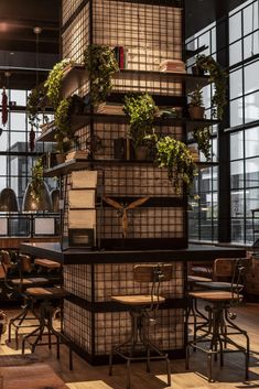 a large stack of books sitting on top of a wooden table in front of windows