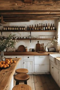 an old fashioned kitchen with wooden counters and shelves filled with bottles, jars and oranges