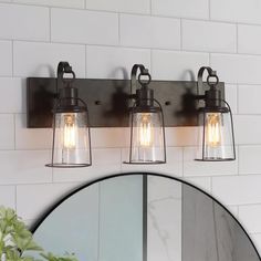 three light bathroom fixture with clear glass and metal caged lights on the wall next to a mirror