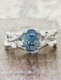 a blue diamond ring with leaves on the sides and an oval stone in the center