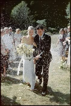 a bride and groom are walking through the confetti