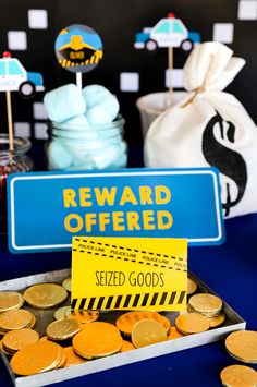 a reward offered sign sitting on top of a tray filled with gold coins and cupcakes