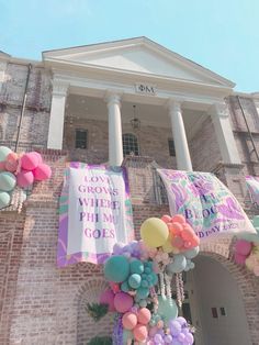 balloons and streamers are hanging from the side of a brick building in front of a doorway