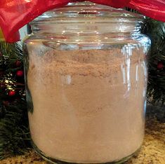 a glass jar filled with sand next to a red bow on top of a counter