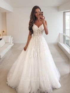 a woman is taking a selfie in her wedding dress while standing in the living room