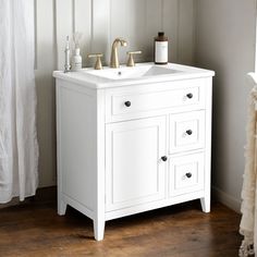 a white bathroom vanity with two faucets and soap dispensers on it