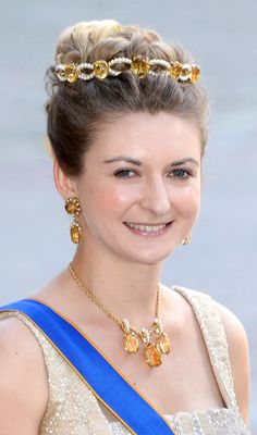 a woman wearing a tiara and smiling at the camera with gold jewelry on her head