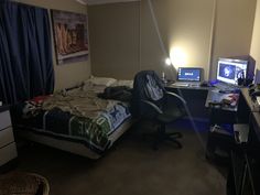 a bed room with a neatly made bed and two computer monitors on the desks