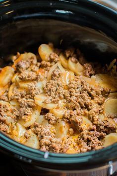 a crock pot filled with pasta and ground beef in the slow cooker, ready to be cooked