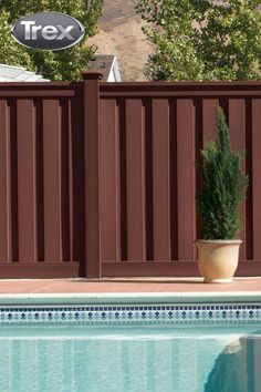 a pool with a tree in it next to a brown fence and a swimming pool