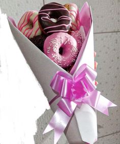 a box filled with assorted donuts on top of a tiled floor next to a wall