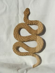 a brown snake laying on top of a white sheet