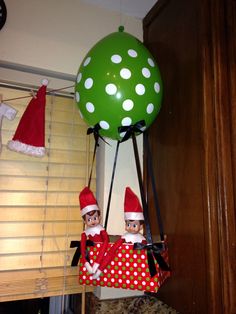 two elfs are hanging from the ceiling in front of a green ballon with white polka dots on it