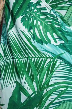 a woman wearing a dress with green leaves on it