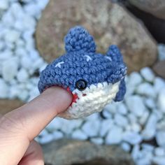 a hand is holding a small crocheted toy shark in it's mouth