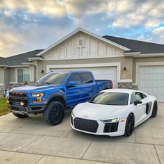 two white and blue trucks parked in front of a house with garage doors on both sides