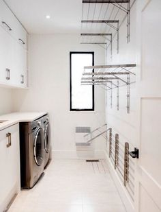 a washer and dryer in a white laundry room with stainless steel shelving