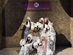 four children dressed up in costumes posing for a photo outside hogwart's express