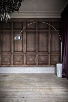 an empty room with wood paneling and a floor lamp