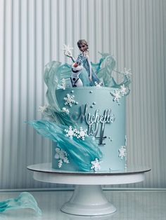 there is a blue cake with frosting on it and an image of a frozen queen