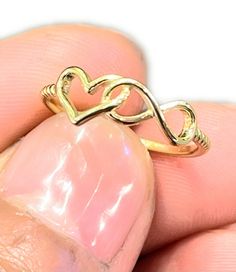 a gold ring with two intertwined hearts on it's side, in the shape of a heart