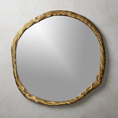 a mirror that is on the wall with a gold frame and round design around it