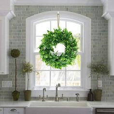 a kitchen sink with a wreath hanging from the window