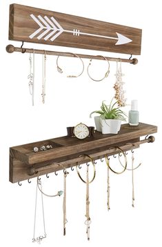 a wooden shelf with two hooks and an arrow hanging from the wall next to a potted plant