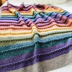 a multicolored crocheted blanket on top of a bed