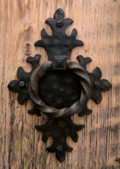 an iron door knockle on the side of a wooden door with a circular handle