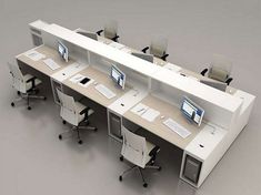 an office cubicle with multiple desks and computer screens on the top, along with chairs