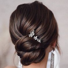 a woman with her hair in a low bun and two crystal hair pins on her head