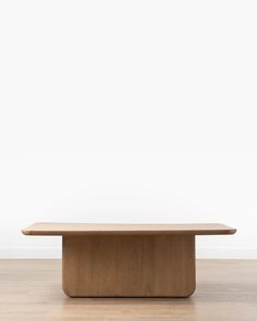 a wooden table sitting on top of a hard wood floor next to a white wall