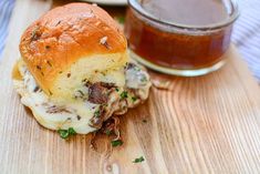 a close up of a sandwich on a cutting board with a jar of sauce in the background