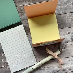 a note pad and pen sitting in a box next to an empty notepad on a wooden table