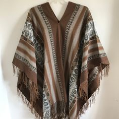 "This is a traditional heavy weight Andean poncho made by one of our most talented weavers. The natural fiber yarn is hand-dyed and woven into beautiful patterns and color arrangements. Perfect to keep you warm around ceremonial fires! There is yarn fringe at the bottom.  One size fits most adults. Unisex. Dimensions: 66\" x 44\" Peruvian woven textiles are incomparable in their quality and beauty. Add this to your collection today! We are a non-profit organization and proceeds from all sales go Bohemian Woven Poncho For Fall, Fall Bohemian Woven Poncho, Traditional Handwoven Poncho For Fall, Bohemian Handwoven One-size Cape, Bohemian One-size Handwoven Cape, Bohemian Woven Winter Shawl, Bohemian Alpaca Shawl One Size, Traditional Alpaca Shawl One Size, Bohemian Alpaca Shawl