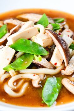 a close up of a bowl of food with noodles and vegetables in sauce on the side