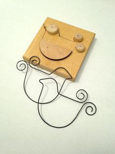 a piece of wood with a smiley face on it's side and two wooden pegs in the middle