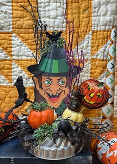 a table topped with halloween decorations on top of a quilted wallpaper covered in orange and green