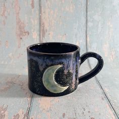 a black coffee cup with a crescent on it