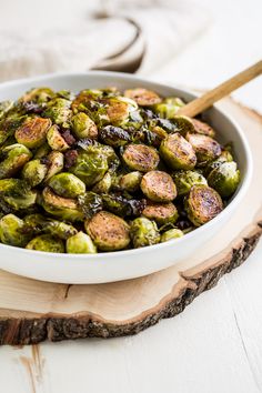 a white bowl filled with brussel sprouts on top of a wooden board