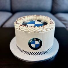 a white cake with blue and black designs on the top is sitting on a table in front of a couch