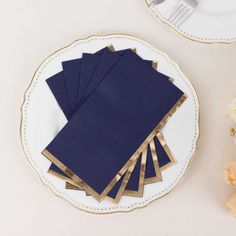 a white plate topped with blue napkins on top of a table next to flowers