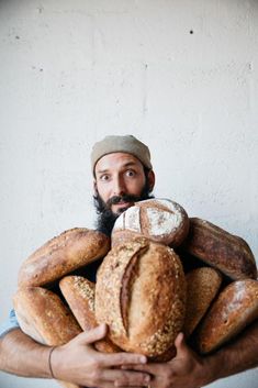 a man with a beard holding a bunch of breads in front of his face